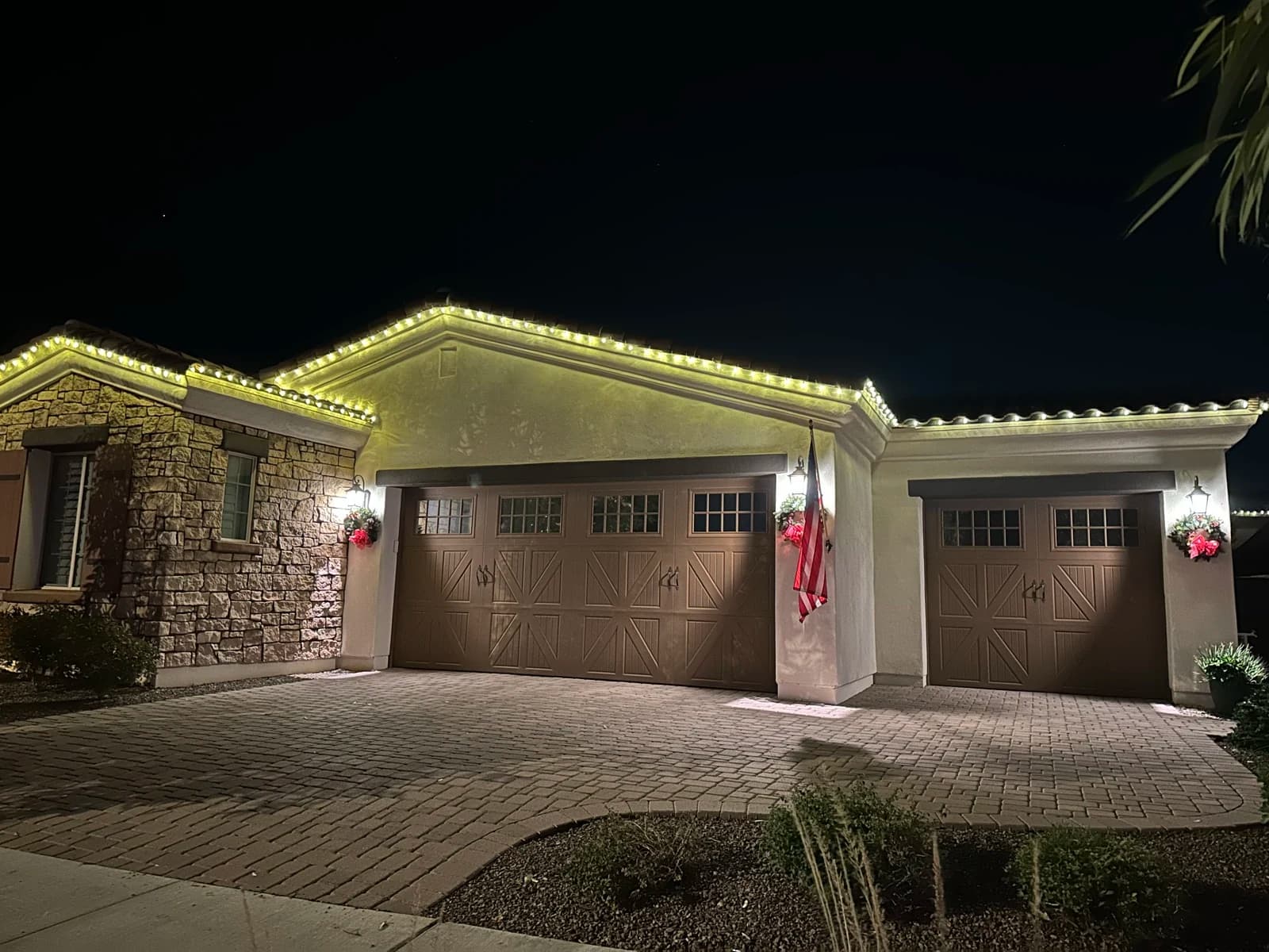 Warm-white holiday roofline lights on a Phoenix home at night