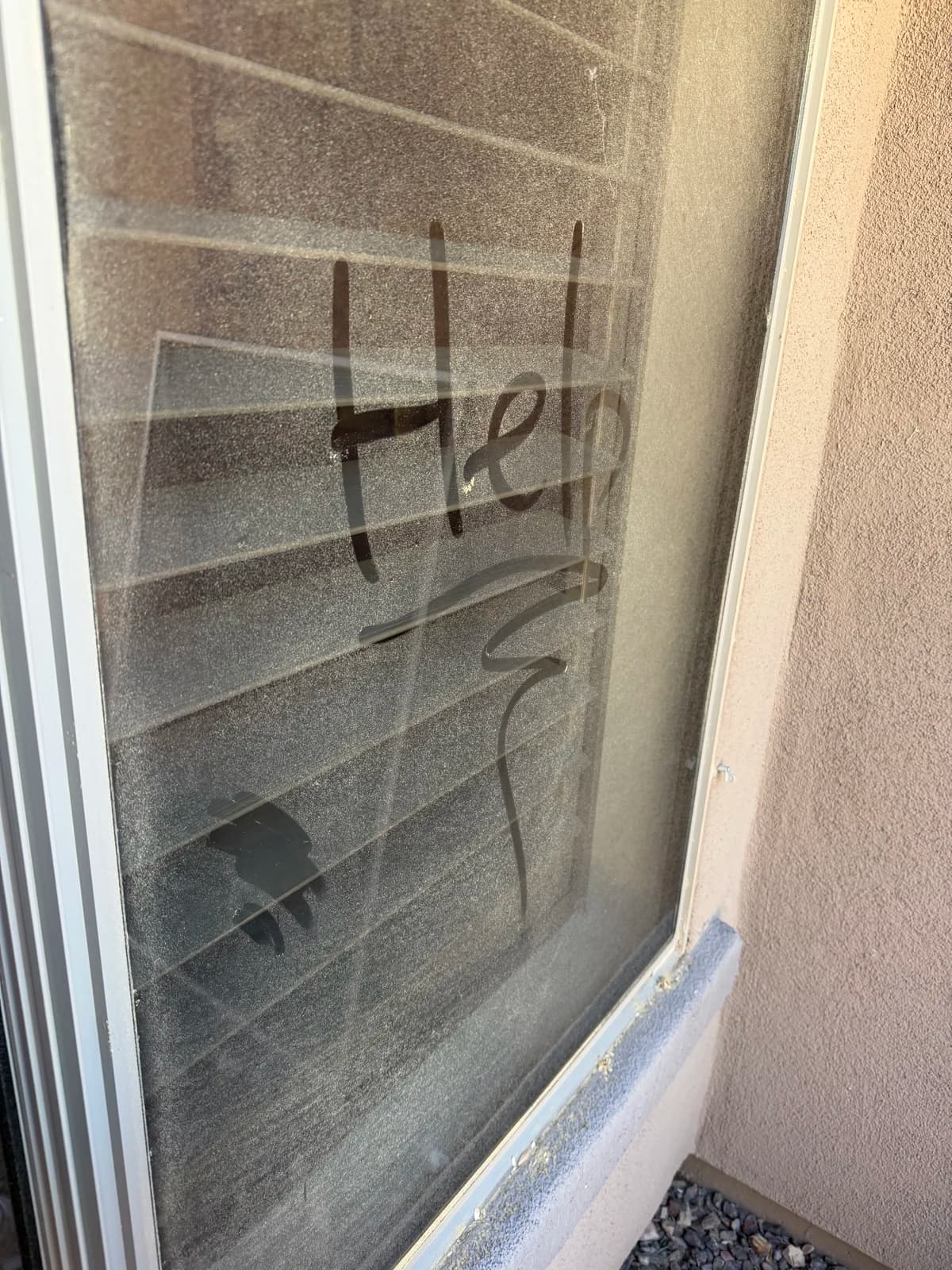 A dusty Phoenix window with "Help" written in the grime, before cleaning