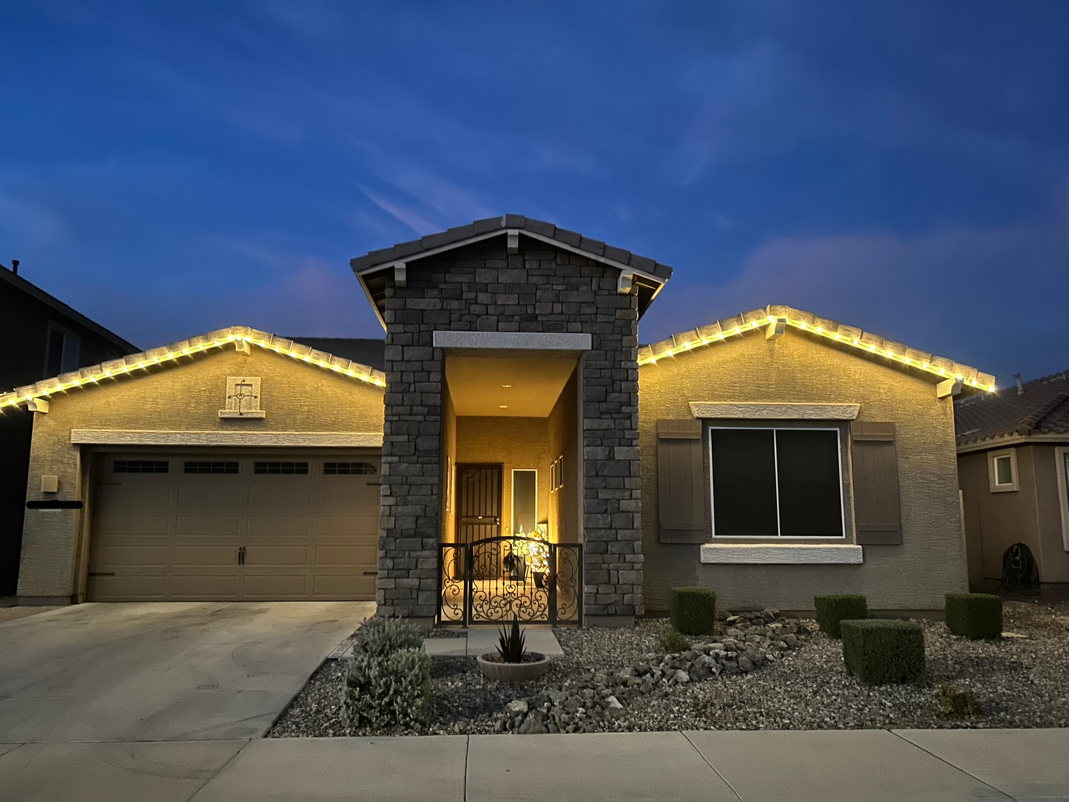 Permanent warm white holiday lighting at dusk on modern Arizona home